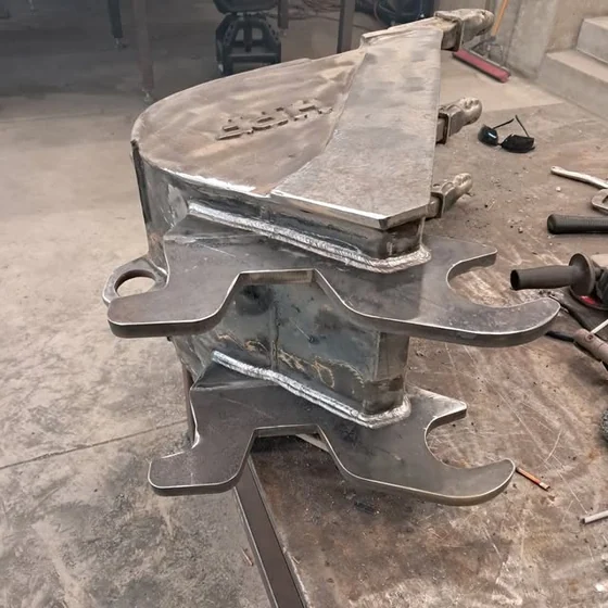 A welded steel bracket assembly with fresh weld beads standing on a shop table